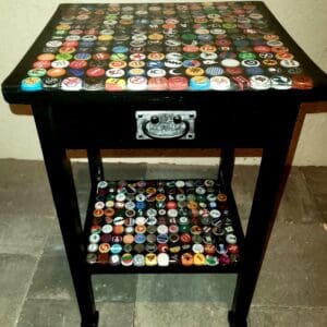 A table with a drawer and a shelf covered in bottle caps.