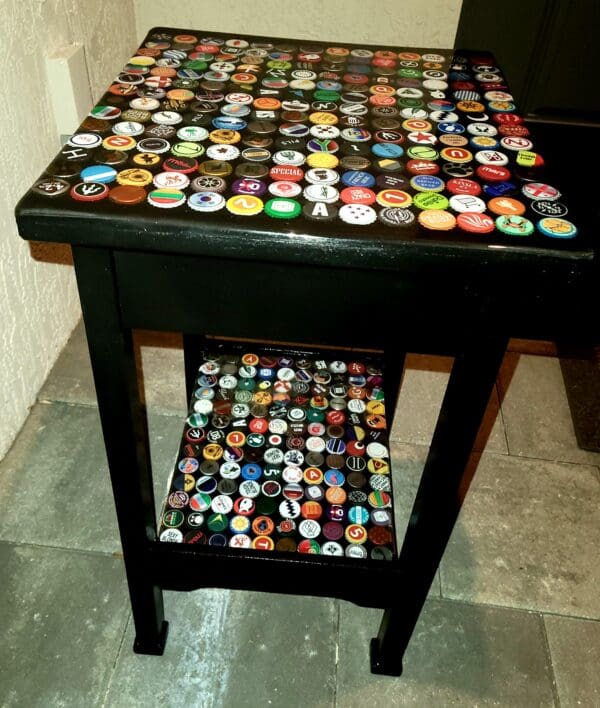 A table with a black top and colorful bottle caps on it.