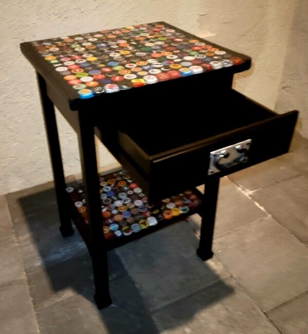 A table with a drawer and shelves made of bottle caps.