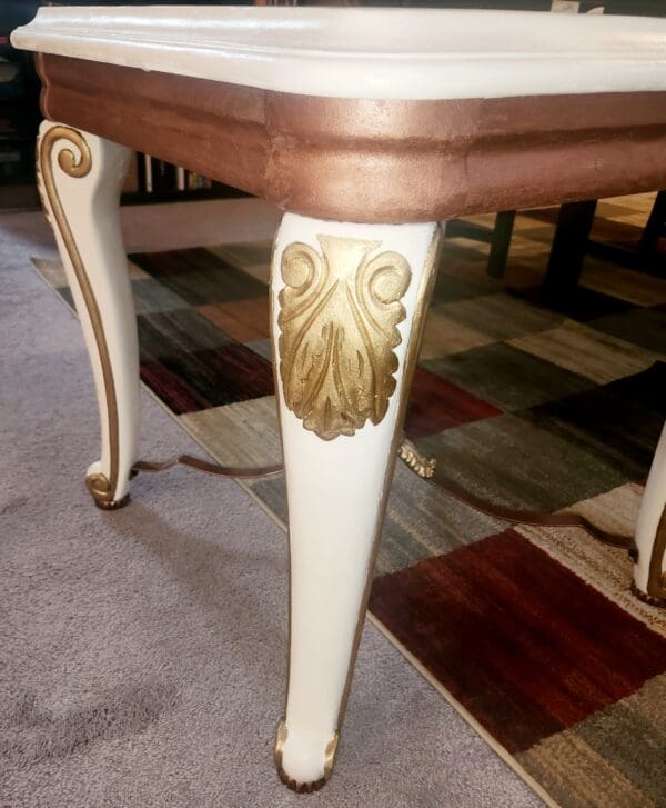 A table with legs painted white and gold.