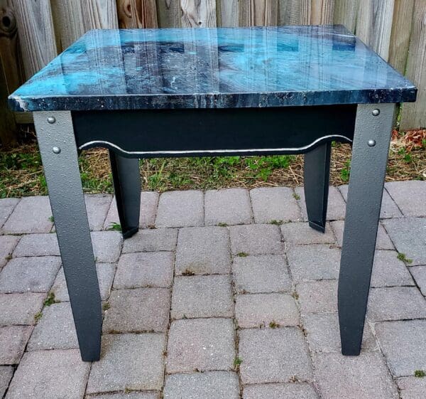 A table with blue and black paint on top of brick.