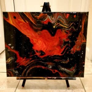 A painting of fire and black paint on top of a table.