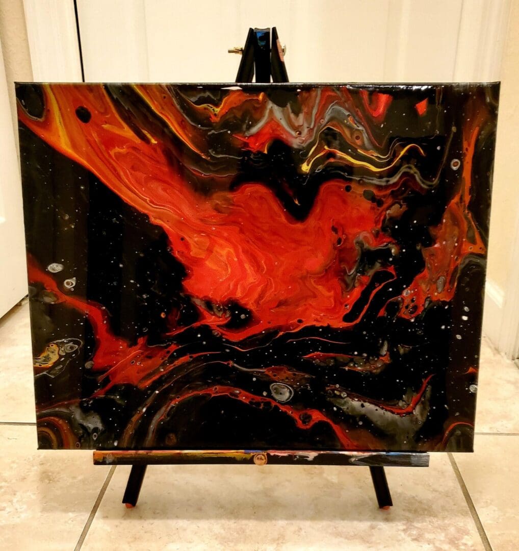 A painting of fire and black paint on top of a table.